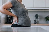 Mittelteil einer schwangeren Frau, die in der Küche steht