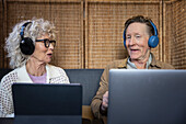 Älteres Paar sitzt im Café und arbeitet an digitalem Tablet und Laptop
