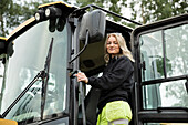 Portrait of smiling woman getting in excavator