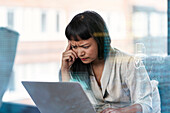 Thoughtful woman with frown forehead using laptop