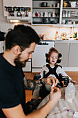 Disabled girl sitting at table in kitchen, father on the foreground