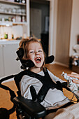 Glückliches behindertes Mädchen im Rollstuhl schaut in die Kamera