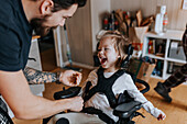Vater kümmert sich um ein glückliches behindertes Kind im Rollstuhl