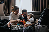 Parents playing with disabled child on sofa