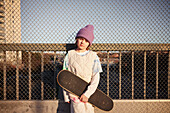Portrait eines Jungen mit Skateboard, der in die Kamera schaut
