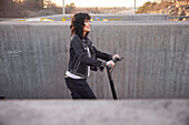 View of young smiling woman riding scooter