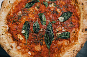 Pizza mit Tomatensauce und Basilikum