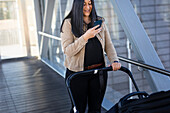 Smiling woman on parental leave  with pram using cell phone