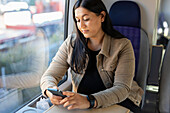 Mittlere erwachsene Frau im Zug benutzt Handy
