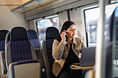 Mittlere erwachsene Frau im Zug mit Laptop