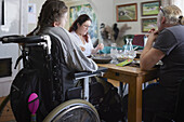 Eltern mit behinderter Tochter im Rollstuhl beim Essen am Esstisch