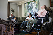 Eltern mit behinderter Tochter im Rollstuhl entspannen sich im Wohnzimmer