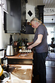 Seitenansicht eines reifen Mannes in der Küche bei der Essenszubereitung