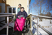 Mutter schiebt Teenager-Tochter im Rollstuhl bei Winterspaziergang