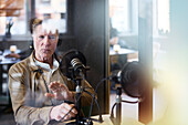 Älterer Mann sitzt und moderiert Podcast oder Radioshow oder Podcast