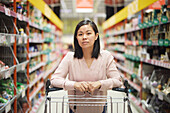 Frau beim Einkaufen im Supermarkt und Blick in die Kamera