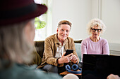 Lächelnder älterer Mann und Frau sitzen im Wohnzimmer und benutzen Laptop