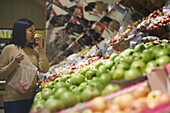 Blick auf eine Frau, die in einem Supermarkt steht und Äpfel auswählt