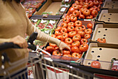 Frauenhand hält Beefsteak-Tomate im Supermarkt