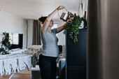 Pregnant woman doing housework and watering plants