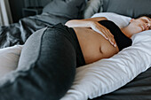 Schwangere Frau schläft auf einem Schwangerschaftskissen im Bett