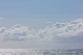 White clouds in a blue sky over the Pacific ocean.