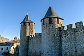 The Château Comtal, Count’s Castle, is a medieval castle in the Cité of Carcassonne, tall towers and wall, and a bridge to a fortified gate. 