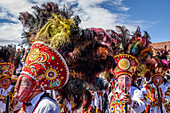 Cusco, a cultural fiesta, people dressed in traditional colourful costumes with masks and hats with feathers. 