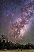 Scorpius and Sagittarius rising, with Scorpius coming up on its side, as seen from New South Wales, Australia, April 2, 2016. Mars is the brightest object left of Antares in Scorpius, with fainter Saturn below the reddish pairing of Mars and its rival Antares. The cyan-colored blob at lower left above the trees is Comet Linear/252P, which passed close to Earth the previous month. Many nebulas and clusters are visible along the Milky Way around the Galactic Centre in Sagittarius, which is rising here.