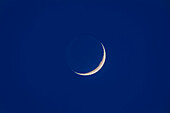 Der zunehmende 3 Tage alte Mond in der Dämmerung mit Erdschein auf der dunklen Seite des Mondes. Man beachte die Bailys-Perlen aus hellen Gipfeln, die das morgendliche Sonnenlicht um den Mondsüdpol einfangen.