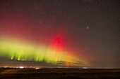 Ein heller grüner Polarlichtbogen mit auffälligen roten Vorhängen, im Osten vor den aufgehenden Wintersternen, mit dem hellen Mars unten in der Mitte und den Plejaden oben rechts. Dies war von zu Hause in Alberta am 26. September 2022.