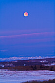 Dies ist die totale Mondfinsternis am 10. Dezember 2011, aufgenommen vom Gelände des Rothney Astrophysical Observatory in der Nähe von Priddis, Alberta, mit Blick nach Westen zu den Rocky Mountains. Es handelt sich um eine 2-Sekunden-Belichtung bei ISO 800 mit der Canon 5DMkII und dem Canon 200mm-Objektiv bei f/4. Die Aufnahme entstand gegen Ende der Totalität um 7:48 Uhr Ortszeit.