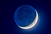 Die 4 Tage alte zunehmende Mondsichel am 8. April 2019 in einer Mischung aus Kurz- und Langzeitbelichtung, um den schwachen Erdschein auf der dunklen Seite des Mondes und den tiefblauen Dämmerungshimmel hervorzuheben, während die Details der hellen, von der Sonne beleuchteten Mondsichel erhalten bleiben.