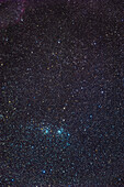 Der berühmte Doppelsternhaufen (NGC 869, rechts und NGC 884, links) im Perseus, in einer Weitfeldaufnahme, die auch den großen und spärlichen Sternhaufen Stock 2, auch bekannt als Muskelmannhaufen, einschließt, ist oben zu sehen, als wäre er von einem quadratischen Sternenrand umrandet. Das Feld ist mit gelben Überriesensternen gefüllt.