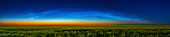 Ein Panorama eines Bogens nachtleuchtender Wolken über einem reifenden Feld gelben Rapses, am 14. Juli 2022 von Süd-Alberta bei Hussar. Dies war gegen 23:20 Uhr MEZ, als die NLCs ihren Höhepunkt erreichten. Sie reichten etwas höher, als sie einige Minuten zuvor am helleren Himmel erschienen, aber ihre Aufnahme ist immer ein Balanceakt zwischen ihrer maximalen Höhe und der Dunkelheit des Himmelshintergrunds, um die schwächeren Strukturen hervorzuheben. Der Vordergrund wird größtenteils von der Dämmerung beleuchtet, und ich habe ihn aufgehellt, um die Rapsfarben und den Farbkontrast zwischen Erd
