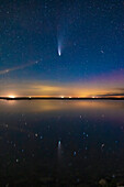Comet NEOWISE (C/2020 F3) reflected in the still waters this night of Crawling Lake in southern Alberta. A dim aurora at right colours the sky magenta. Lingering twilight colours the sky blue. A meteor or more likely a flaring satellite appears at right and is also reflected in the water. Even in this short exposure, the two tails — dust and ion — are visible. This was July 20, 2020.