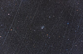 Dies ist NGC 457, der ET- oder Eulenhaufen in Kassiopeia, in einem Stapel von Bildern, die die Gesamtzahl der in den 36 Minuten Gesamtbelichtungszeit dieser Nacht aufgezeichneten Satellitenspuren zeigen. Zufälligerweise rahmen die Spuren das Hauptmotiv ein, aber die Anzahl der Satelliten über uns macht es fast unmöglich, eine Langzeitbelichtung zu machen, vor allem zu Beginn oder am Ende einer Nacht, ohne mindestens eine Satellitenspur, wenn nicht sogar mehr, pro Bild aufzunehmen. Einige der parallelen Streifen könnten Starlink-Satelliten sein.