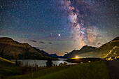 The galactic core area of the Milky Way over Waterton Lakes National Park, Alberta with the pairing of giant planets from summer 2020. Jupiter is the bright object at centre, with Saturn dimmer to the left (east) of Jupiter. In 2020 the two planets were close together in the summer sky. Sagittarius is at right. The Prince of Wales Hotel is the bright light source. This was July 13-14, 2020.