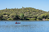 A woman kayaking on a reservoir by Villa San Agustin in San Juan Province, Argentina. Another man swims nearby.