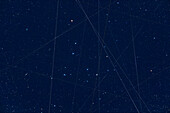 This is a stack of images demonstrating the number of satellites passing through the field of a wide-field telescope over a little more an hour. The field frames the Coma Berenices star cluster. This is from my home at 51° North, a latitude more prone to seeing satellites lit by the Sun well into the evening, if not all night closer to summer solstice. Most trails are north-south so they are likely NOT Starlink satellites but polar orbiting satellites. Interesting that the trails have different colours, likely from their solar panels or other structures reflecting blue and gold tints.