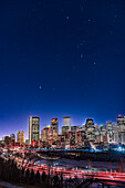 An urban nightscape of the constellations of Orion and Canis Major over the skyline of Calgary on January 18, 2018, on a very clear and moonless winter night, allowing stars to show up fairly well despite the light pollution. Sirius is above the Bow Tower building at left.