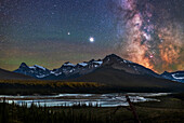 Jupiter (brightest), Saturn (to the left), and the Milky Way over the Saskatchewan River and the area of Howse Pass, on July 26, 2020. Mount Cephren is at left; the scene is framed to include Cephren. The nebulas and star clouds of the galactic centre area at right show up well on this very clear night. The bright Small Sagittarius Starcloud, aka M24, is most obvious, flanked by the star clusters M23 and M25 to the side, and the nebulas M17 and M16 above, and M8 and M20 below. The fuzzy globular cluster M22 is to the left of the large Lagoon Nebula, M8. Green airglow tints the sky.