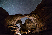 Ein Fotograf verwendet ein helles Licht, um den Double Arch im Arches National Park, Utah, in einer dunklen Nacht zu beleuchten, bevor der Mondaufgang für natürliche Beleuchtung sorgt. Die Verwendung von hellem Licht zum Malen von Landschaften bei Nacht ist weit verbreitet, erzeugt aber oft eine künstliche Beleuchtung.