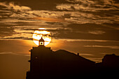 Die Sonne im Einklang mit der Silhouette des Leuchtturms von Luarca, Asturien, Spanien, Europa