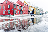 Tourist walking near the multicolored houses of Tromso in winter, Tromso, Norway, Scandinavia, Europe