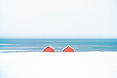 Red cabins in the snow overlooking the frozen sea, Troms county, Norway, Scandinavia, Europe