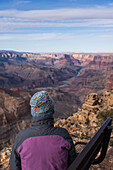 USA, Arizona, Rückansicht einer auf einer Bank sitzenden Touristin im Grand Canyon National Park