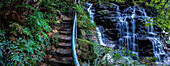 Australia, NSW, Wentworth Falls, Stairs and waterfall in forest in Blue Mountains National Park