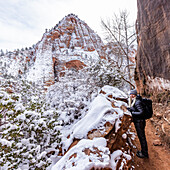 USA, Utah, Springdale, Zion National Park, Ältere Frau beim Wandern in den Bergen im Winter