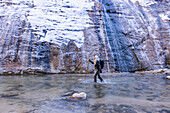 USA, Utah, Springdale, Zion National Park, Senior woman crossing river while hiking in mountains